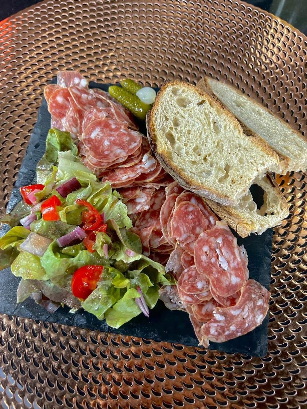 Une planche de charcuterie et de pain avec une salade de tomates